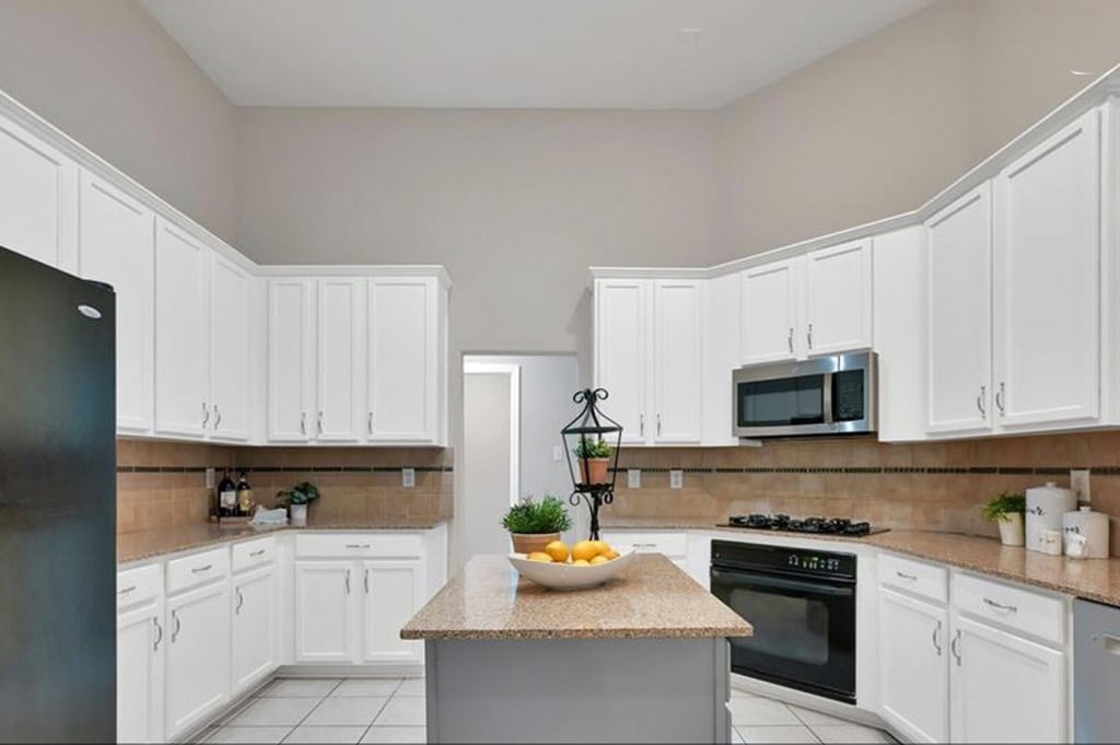 Modern white kitchen with granite countertops, stainless steel appliances, and a central island ideal for cooking and gatherings. Bright and spacious interior design with clean lines.