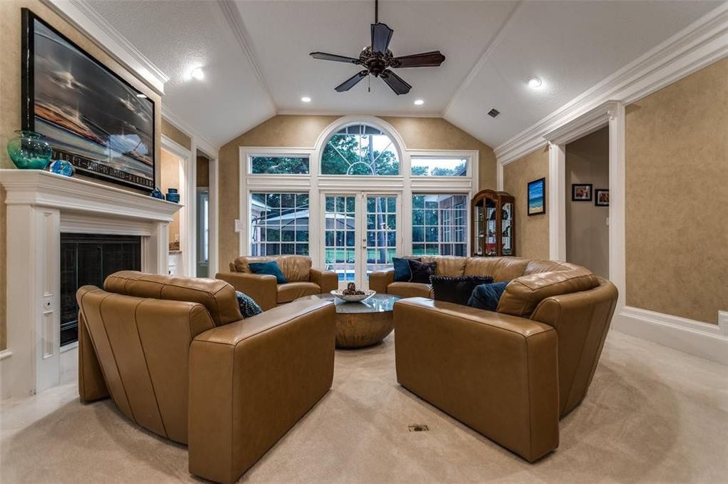 Cozy living room interior with leather sofas, large bay window, and elegant crown molding in a modern home.